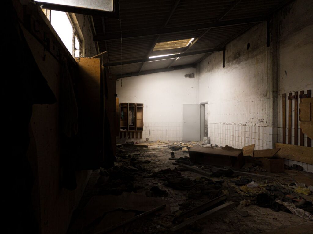 Explore the haunting atmosphere of a dimly lit abandoned room filled with decay and debris.